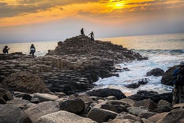 Tourists walking on the gianst causeway at sunset